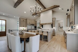 A modern kitchen with a central island, wooden beams, and a chandelier. - Spacious Lake Escape! Lakefront w/ Dock + Kayaks~Sleeps 10~2 Living Areas (Hot Springs)