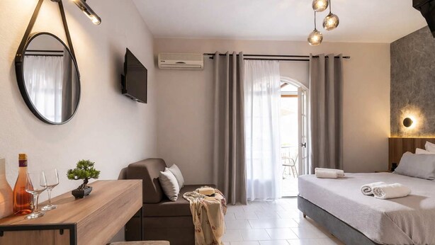 Quarto de hotel moderno com cama, escrivaninha, cadeira, televisão e janela com cortinas.
