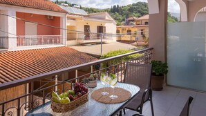 Uma varanda com uma mesa, uma cesta de frutas e dois copos de bebida.
