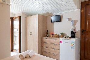 Une chambre à coucher comprenant un lit, une armoire en bois, une télévision, une machine à café et un réfrigérateur.