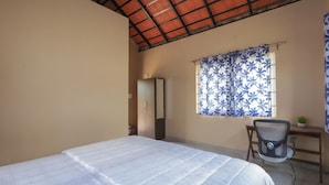Une chambre à coucher avec un lit, un bureau, une chaise et une fenêtre avec des rideaux.