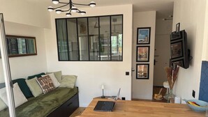Un espacio habitable moderno con un sofá, una mesa de comedor de madera y un ordenador portátil.
