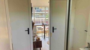 Una habitación con puerta de vidrio corredera que da a un balcón con mesa y sillas.