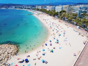Ein Strand mit klarem türkisblauem Wasser, einem Sandstrand und einer Reihe von Gebäuden entlang der Küste.