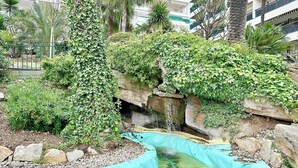 Un jardin aménagé avec un élément aquatique, entouré de verdure et délimité par un mur de pierres.
