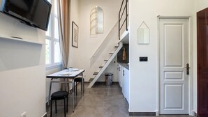 Moderni keittiö, jossa on ruokailutila, portaikko ja seinälle asennettu televisio.