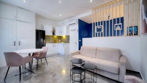 Ein modernes Wohnzimmer mit einer Couch, einem Esstisch mit Stühlen und einer Küche im Hintergrund.