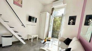 Een moderne woonkamer met een trap, een flatscreen televisie, een bank en een eethoek.