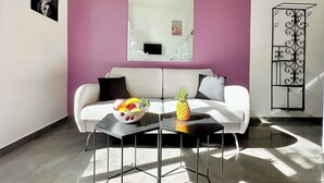 Een moderne woonkamer met een witte bank, een zwarte salontafel en een schaal met fruit.