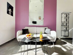 Ein modernes Wohnzimmer mit einem weißen Sofa, einem schwarzen Couchtisch und einer Obstschale.