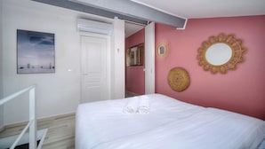 A bedroom with a bed, a white door, a mirror, and a painting on the wall. - App. Suzette Duplex - 500m FROM THE BEACH (Cannes)