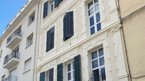 Un immeuble à plusieurs étages doté de balcons, une enseigne indiquant « VILL LA LOUSIETTE », et un scooter garé.