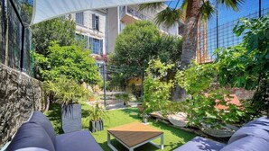 Une cour avec une table en bois, des chaises longues et une pergola offrant de l’ombre.