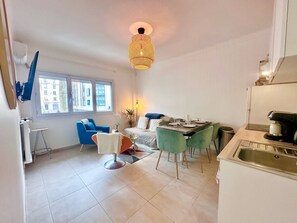 Ein modernes Apartment mit Essbereich, Küche und einem großen Fenster.