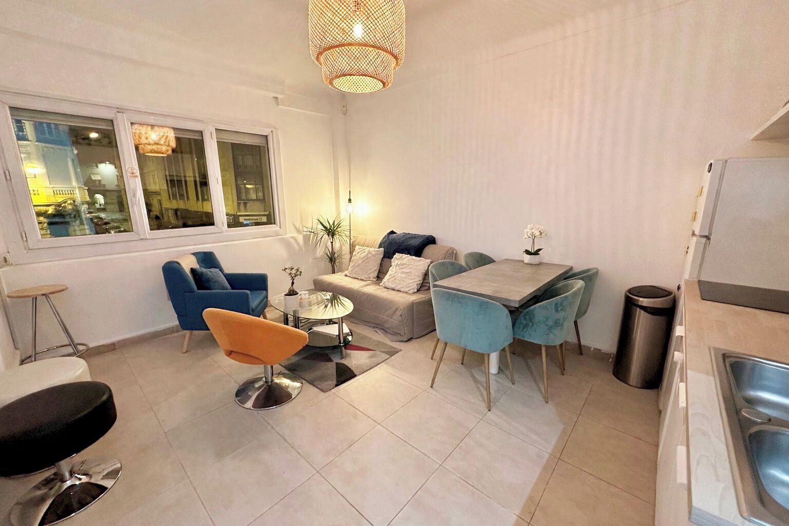 A compact living space with a dining area, a sofa, a coffee table, and a kitchenette.