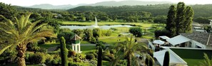 Ein Golfplatz mit Teich, Palmen und einem kleinen weißen Gebäude.