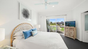 Ein Hotelzimmer mit Bett, Fernseher, Deckenventilator und Blick ins Freie.