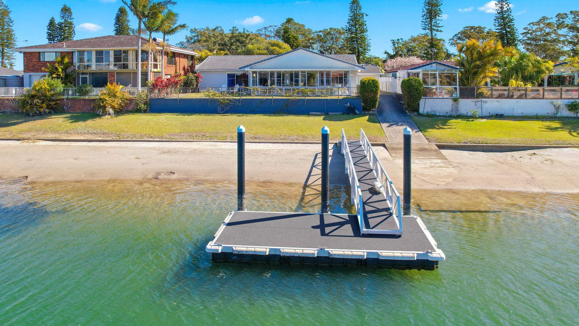 A waterfront property with a dock, a house with a covered patio, and a clear view of the water.