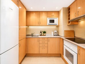 A kitchen with wooden cabinets, a Bosch refrigerator, a microwave, a coffee maker, and a stove. - Sol Wave House with Sea Views, Wi-Fi and Air Conditioning (Magaluf)