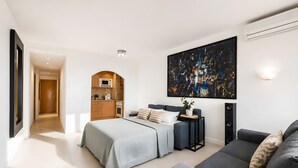 A modern hotel room with a bed, a sofa, a kitchen area, and a large abstract painting on the wall. - Sol Wave House with Sea Views, Wi-Fi and Air Conditioning (Magaluf)