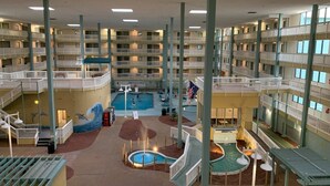 Interior de hotel de varios niveles con piscina central, balcones y zona de hidromasaje.
