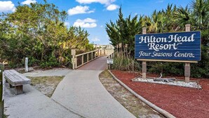 Un sendero conduce al Centro Four Seasons del Resort Hilton Head, rodeado de exuberante vegetación.