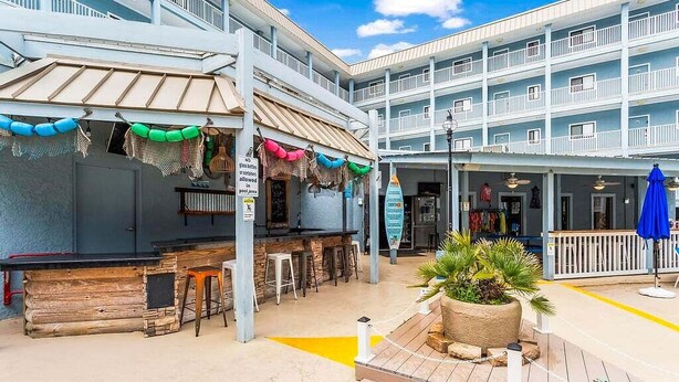 Un hotel de varios niveles con zona de piscina, bar al aire libre y asientos.