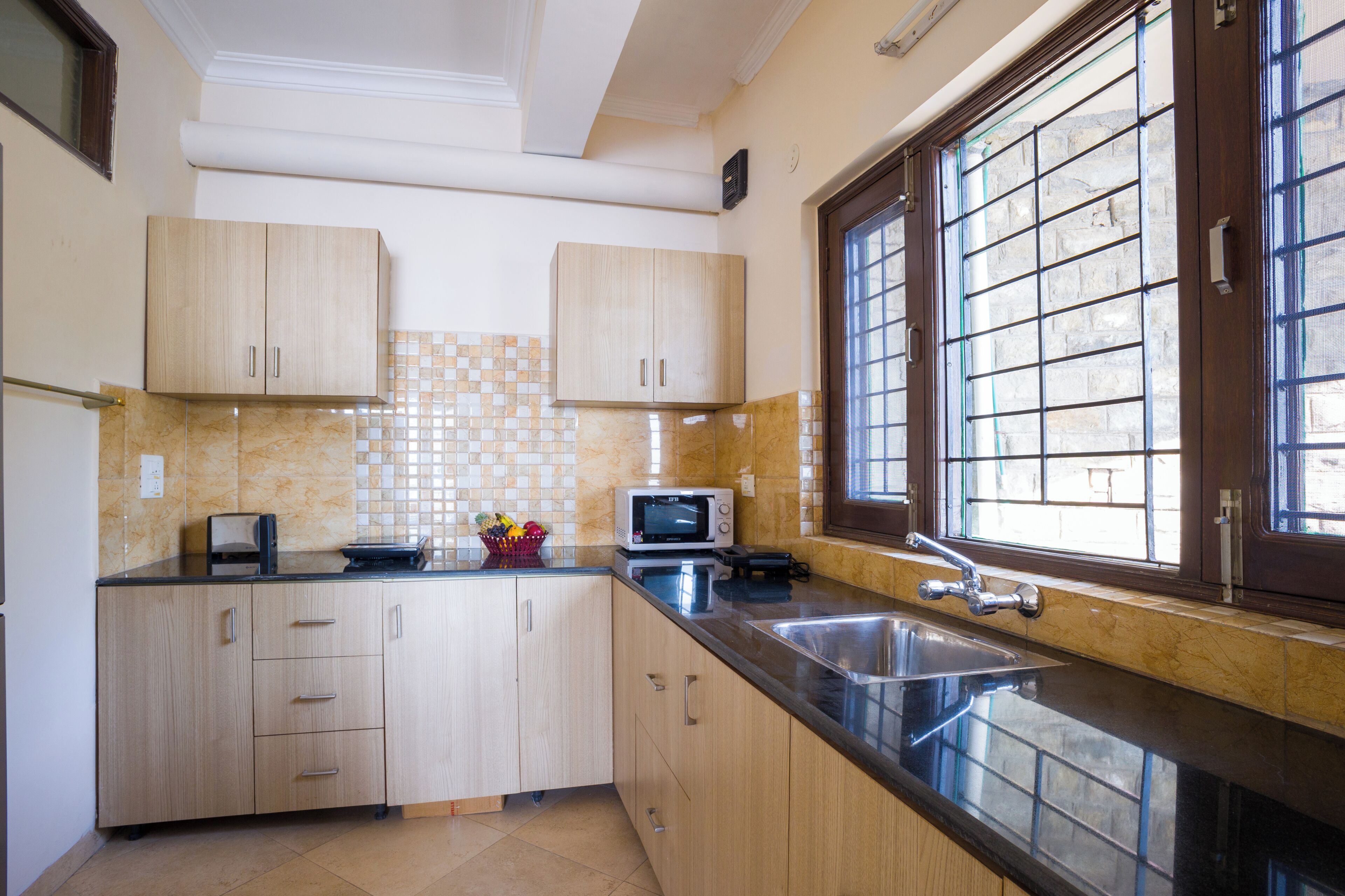 A kitchen with wooden cabinets, a microwave, a sink, and a window with a grid pattern.