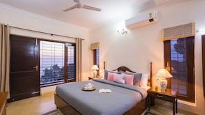 Ein Hotelzimmer mit Bett, Nachttischlampen, Deckenventilator, Klimaanlage und einem Fenster mit Blick.