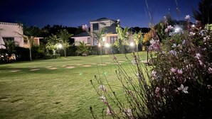 Zona residencial bien iluminada con césped, una casa y vegetación circundante.