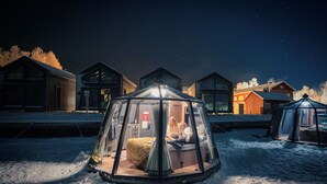 Ett snötäckt utomhusområde med en glasförsedd konstruktion som inrymmer två personer.
