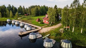 En fastighet vid en sjö med flera kupolformade byggnader, en brygga och ett rött hus.