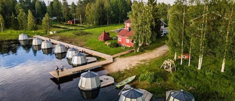 A lakeside property with several dome-shaped structures, a dock, and a red house.