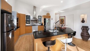 Una cocina moderna con una isla central, electrodomésticos de acero inoxidable y un jarrón grande.