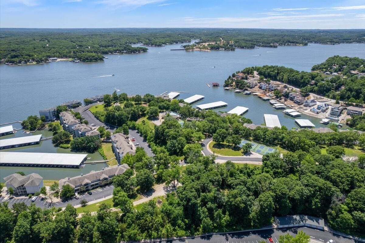 An aerial view of a waterfront property with multiple buildings, a marina, and lush greenery.