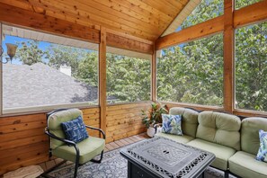 A wooden-paneled room with a sofa and a chair, large windows, and a view of trees. - Lakefront Near State Park w/ Dock, Kayaks, Bunk Room & Multi-Level Decks (Osage Beach)