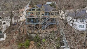 A two-story house with a balcony, surrounded by trees and other houses. - Lakefront Near State Park w/ Dock, Kayaks, Bunk Room & Multi-Level Decks (Osage Beach)
