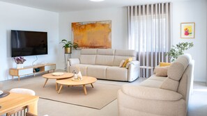 A modern living room with a sofa, coffee table, TV, and artwork.