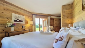Een slaapkamer met houten lambrisering, een groot bed, een nachtkastje met lamp en een schilderij aan de muur.