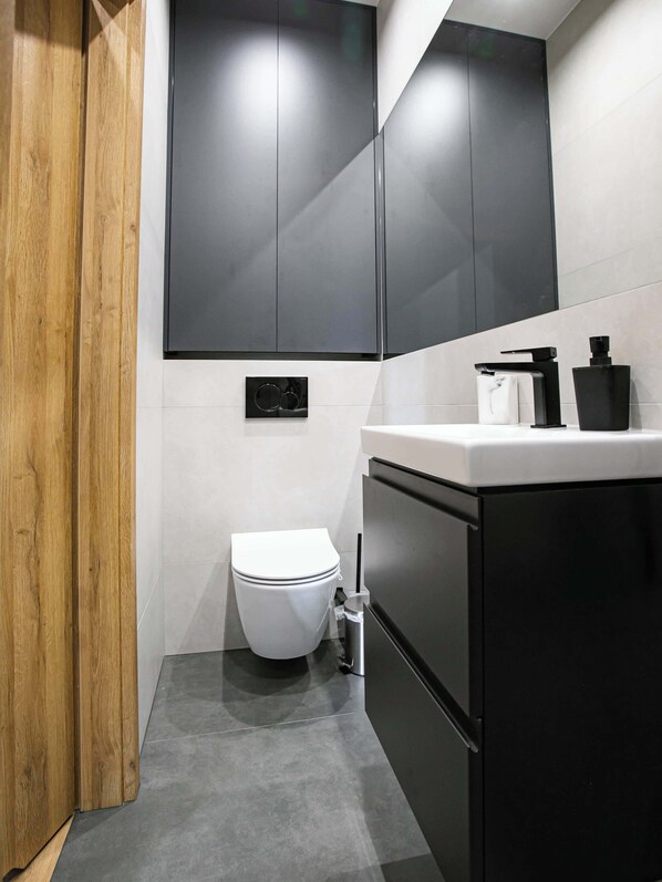 Un baño moderno con inodoro, lavamanos y un mueble.