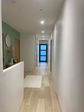 A hallway with a white floor, a white rug, and a door at the end. - Dominant house overlooking pine forest (Les Matelles)