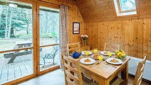A wooden cabin with a dining table set for breakfast, a bench outside, and a view of the forest. - Stunning private villa for 8 guests with WIFI, TV, terrace and pets allowed (Cannich)