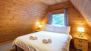 A wooden-paneled room with a bed, two bedside tables with lamps, and a window with curtains. - Stunning private villa for 8 guests with WIFI, TV, terrace and pets allowed (Cannich)