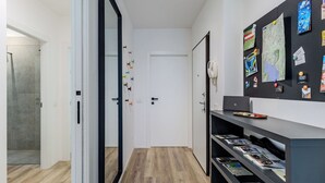 A hallway with a wooden floor, a white door, and a wall with various items pinned to it. - Lovely apartment for 6 guests with A/C, WIFI, TV and patio (Riva Del Garda)