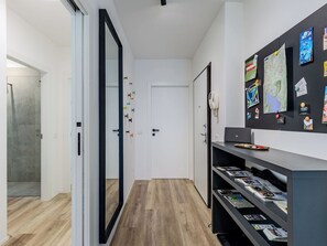 Ein Flur mit Holzboden, einer weißen Tür und einer Wand mit verschiedenen angehefteten Gegenständen.