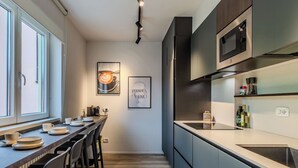 A modern kitchen with a dining area, featuring a long counter, chairs, and a coffee machine. - Lovely apartment for 6 guests with A/C, WIFI, TV and patio (Riva Del Garda)