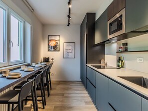 Eine moderne Küche mit Essbereich, ausgestattet mit einer langen Arbeitsplatte, Stühlen und einer Kaffeemaschine.