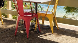 A balcony with a table and chairs overlooking a marina with boats and buildings. - Hotel Emerald (Potts Point)