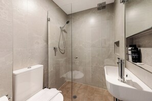 A modern bathroom with a glass-enclosed shower, a white sink, and a toilet. - Hotel Emerald (Potts Point)