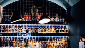 A bar with shelves of liquor bottles, a cash register, and bar stools. - Hotel Emerald (Potts Point)